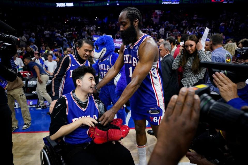 Philadelphia 76ers' James Harden gives his sneakers to John Hao after Game 4 in an NBA basketball Eastern Conference semifinals playoff series, Sunday, May 7, 2023, in Philadelphia. Harden invited Hao, a student severely wounded in a Feb. 13 mass shooting at Michigan State University, to view the game. (AP Photo/Matt Slocum)