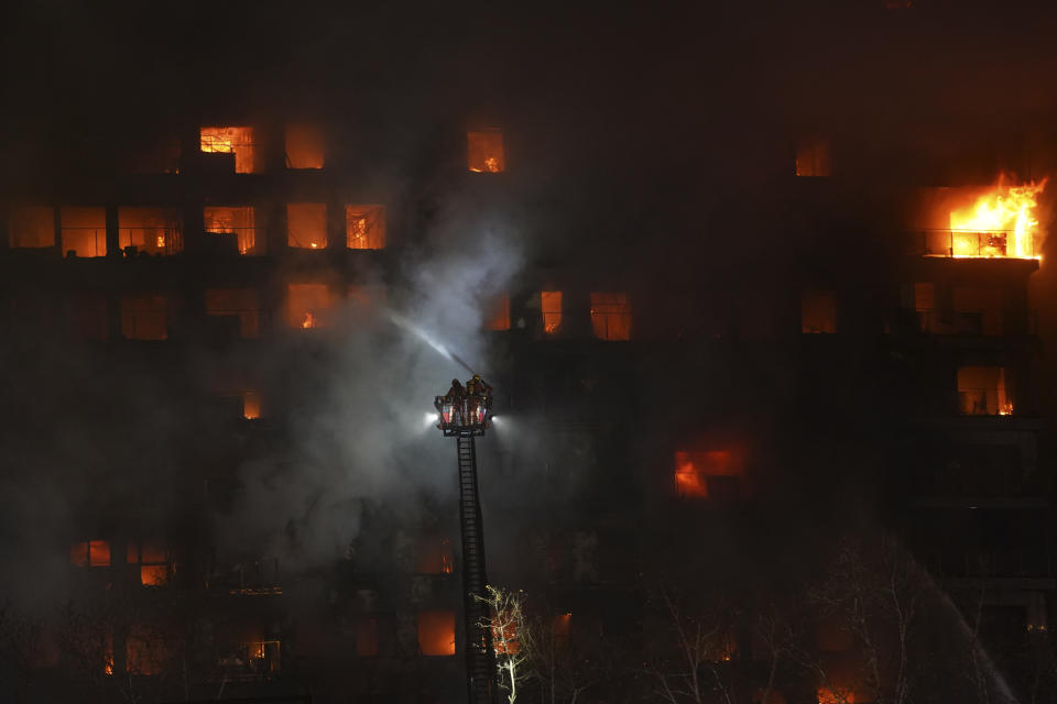 Firefighters work as a housing block burns in Valencia, Spain, Thursday, Feb. 22, 2024. A fire has engulfed two residential buildings in the eastern Spanish city of Valencia, injuring at least 13 people. Flames can be seen bursting out from windows and balconies of the 14-story residential building where it is reported to have started. Emergency service reports say at least 13 people were injured. Firefighters have rushed to the area located on an avenue in the city center. Some people were trapped on balconies. (AP Photo/Alberto Saiz)