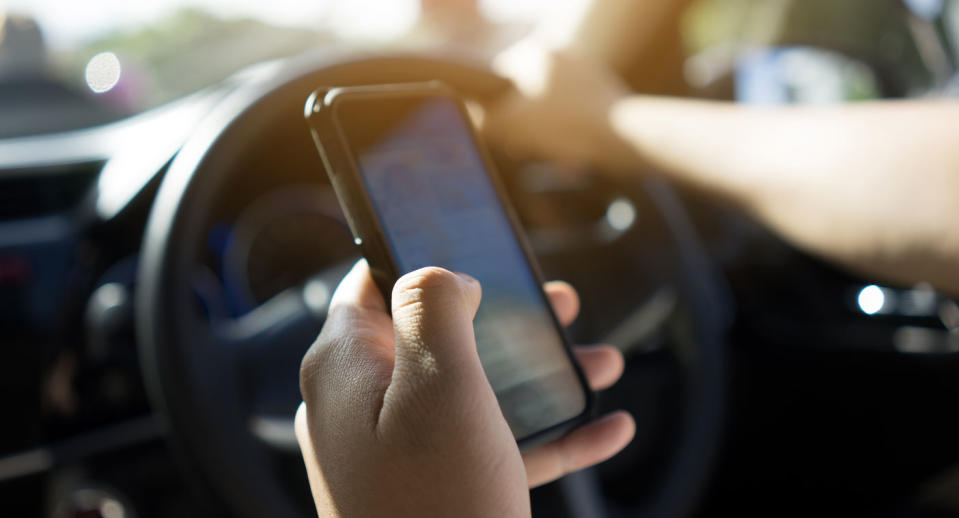 A person pictured using a mobile phone while driving.