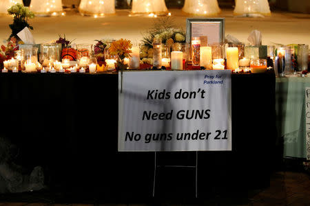 A sign is seen next to candles and tributes at a park where crosses were placed to commemorate the victims of the shooting at Marjory Stoneman Douglas High School, in Parkland, Florida, U.S., February 16, 2018. REUTERS/Carlos Garcia Rawlins