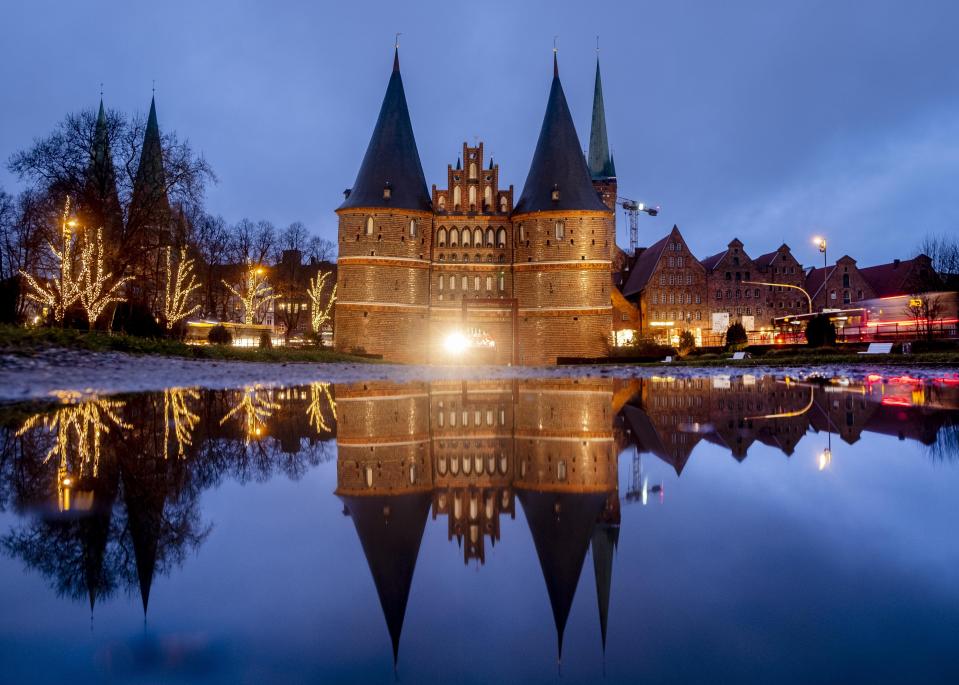 The medieval Holstentor is reflected in water in Luebeck, Germany, Monday, Jan. 4, 2021. The German government will decide about further restrictions to avoid the outspread of coronavirus on Tuesday. (AP Photo/Michael Probst)