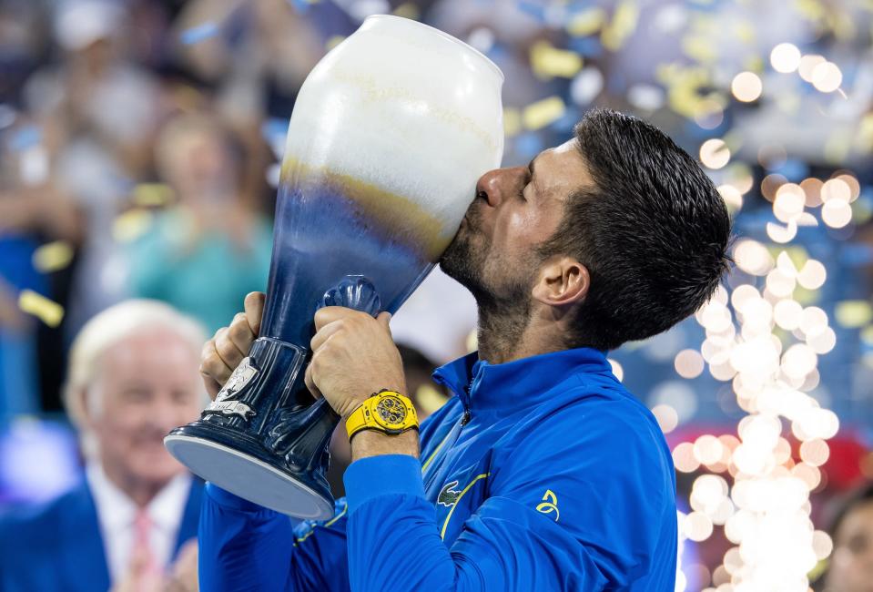 Novak Djokovic hoists the trophy after winning the men's singles final of the Western & Southern Open at Lindner Family Tennis Center on August 20, 2023