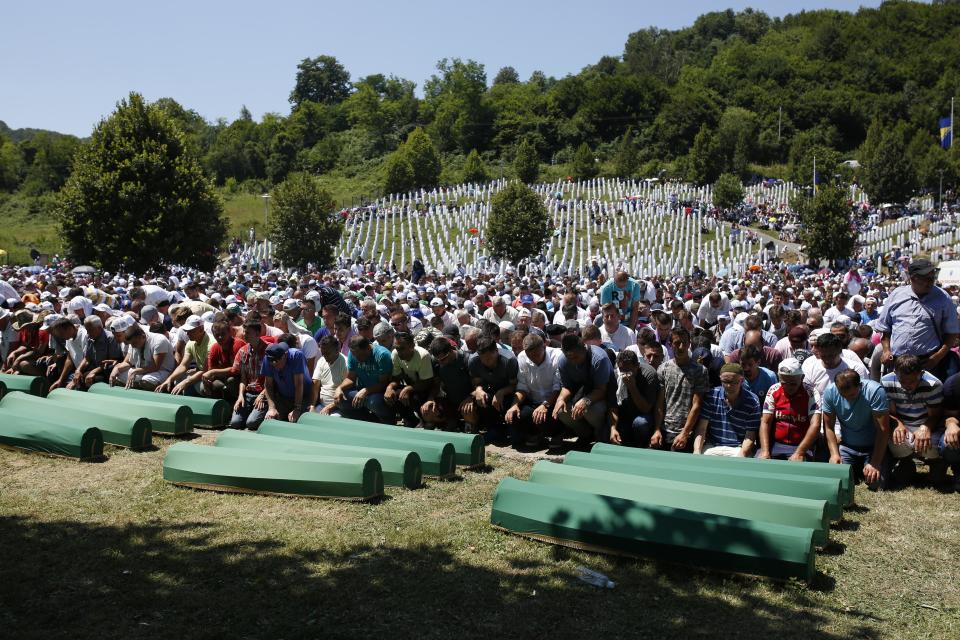 FILE- In this Tuesday July 11, 2017, file photo, Bosnian Muslim people pray in front of coffins during a funeral ceremony for dozens of newly identified victims of the 1995 massacre, at the memorial centre of Potocari near Srebrenica, 150 kms north east of Sarajevo, Bosnia. The Dutch defense minister announced Wednesday that the government will pay veterans of a United Nations peacekeeping mission that failed to prevent the massacre of thousands of Bosnian Muslims by Bosnian Serbs in 1995 5,000 euros each as a "gesture and token of appreciation" for their service in horrific circumstances. (AP Photo/Amel Emric, File)