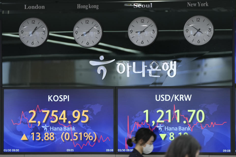 An employee of a bank walks by screens showing the Korea Composite Stock Price Index (KOSPI), left, and the foreign exchange rate between U.S. dollar and South Korean won at a foreign exchange dealing room in Seoul, South Korea, Wednesday, March 30, 2022. Asian stock markets followed Wall Street higher on Wednesday as talks on ending Russia's war on Ukraine appeared to make progress. (AP Photo/Lee Jin-man)