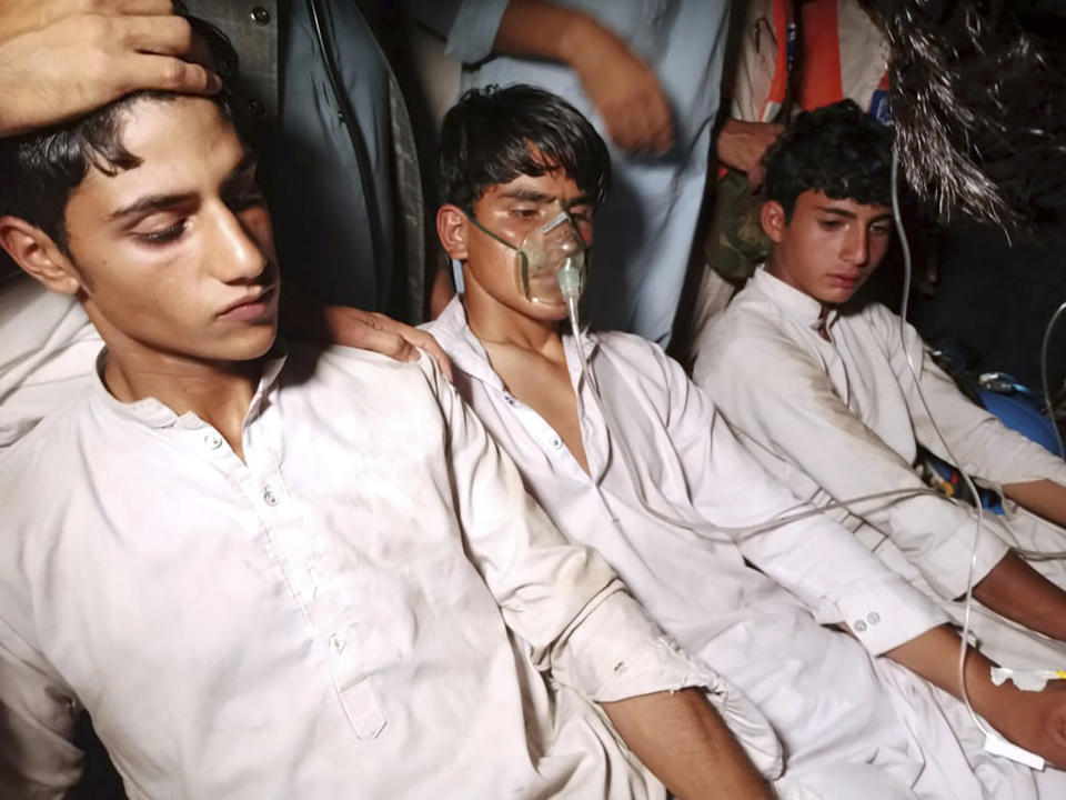 Youngsters, left, who were trapped in a broken cable car, receive first aid following their rescue, in Pashto village, a mountainous area of Battagram district in Pakistan's Khyber Pakhtunkhwa province, Tuesday, Aug. 22, 2023. Army commandos using helicopters and a makeshift chairlift rescued eight people from a broken cable car dangling hundreds of meters (feet) above a canyon Tuesday in a remote part of Pakistan, authorities said. (AP Photo/Nasir Mahmood)