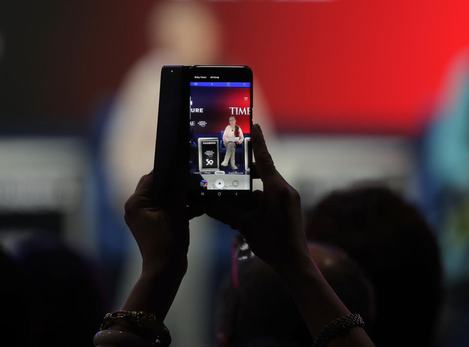 A woman takes pictures of Swedish environmental activist Greta Thunberg at the World Economic Forum in Davos, Switzerland, Tuesday, Jan. 21, 2020. The 50th annual meeting of the forum will take place in Davos from Jan. 20 until Jan. 24, 2020. (AP Photo/Markus Schreiber)