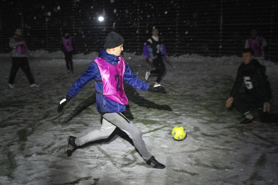 Men take part in a soccer game during a blackout in Irpin, Kyiv region, Ukraine, Tuesday, Nov. 29, 2022. For soccer lovers in Ukraine, Russia's invasion and the devastation it has wrought have created uncertainties about both playing the sport and watching it. For Ukrainians these days, soccer trails well behind mere survival in the order of priorities. (AP Photo/Andrew Kravchenko)