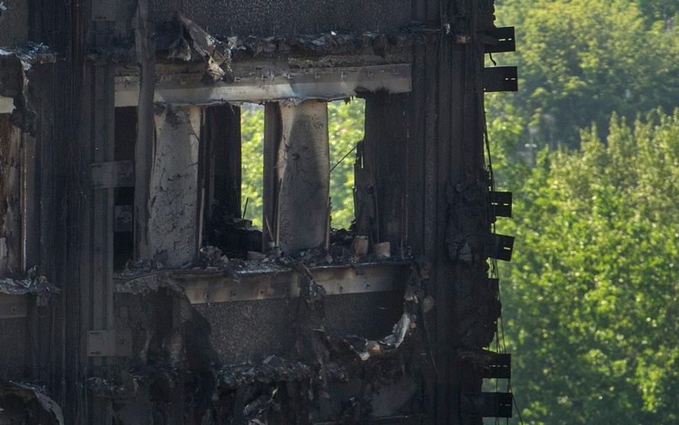 Cladding on Grenfell Tower is seen smouldering after the fatal blaze in June - JULIAN SIMMONDS