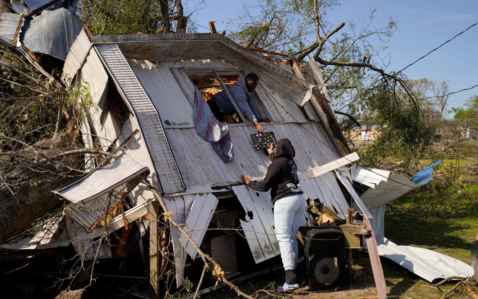 Jeremiah Stapleton, 18, passes a laptop to a family member from the window of his grandfather's home - REUTERS/Cheney Orr