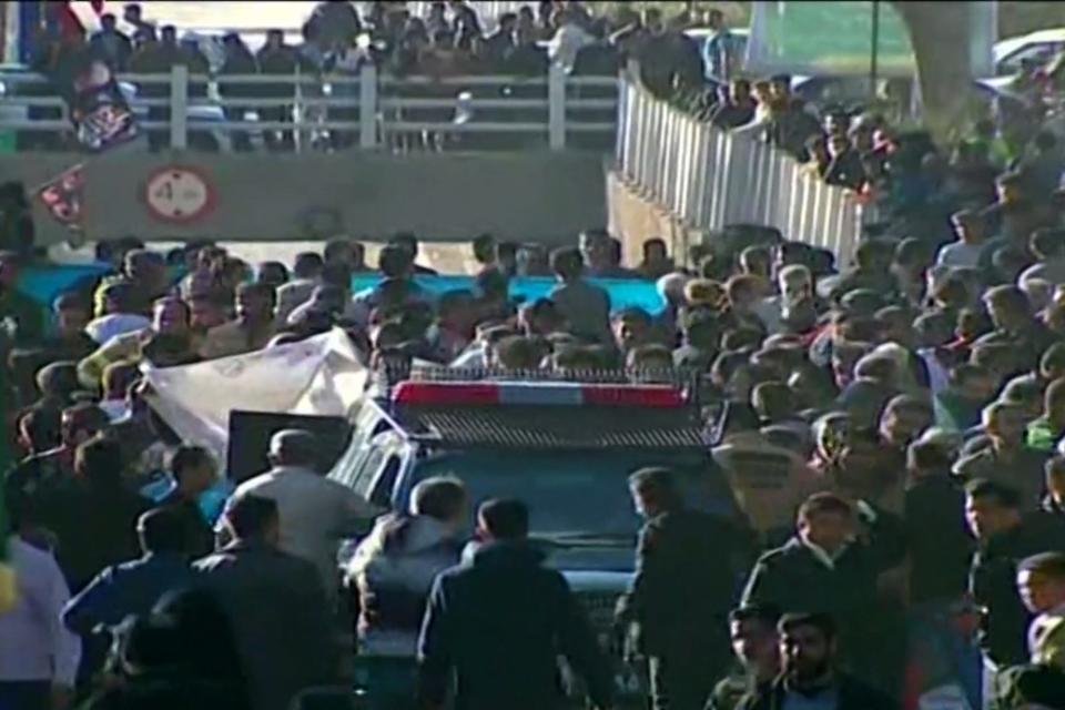 An image grab from a video released by the state-run Iran Press news agency on Jan. 3, 2024, shows a police vehicle surrounded by a crowd near the site where explosions erupted in the southern Iranian city of Kerman.