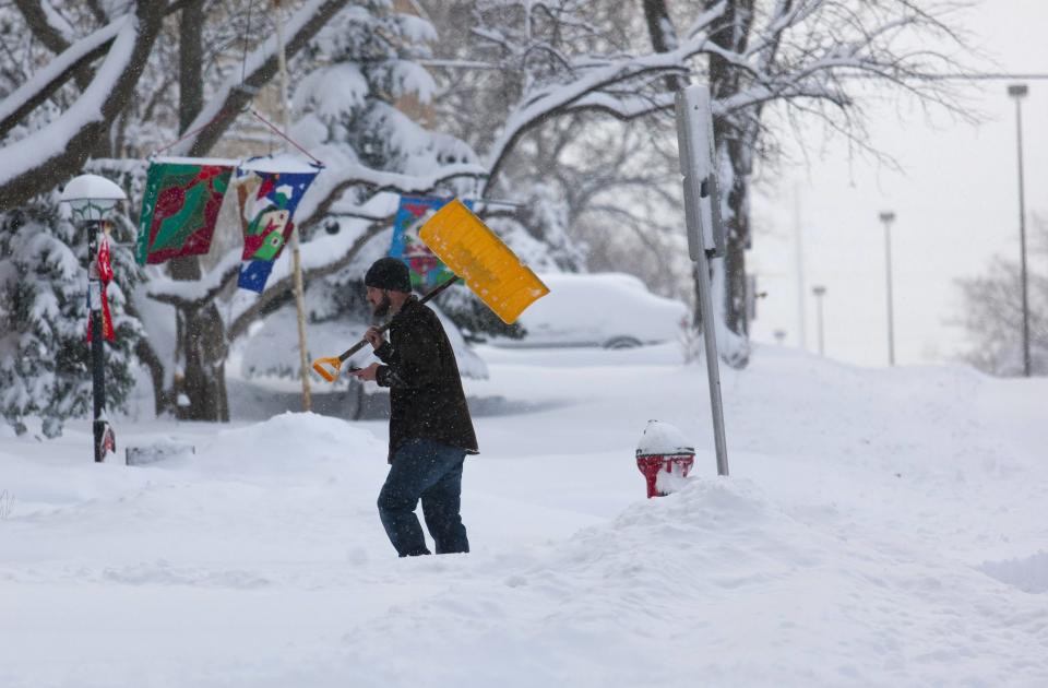 A man carries a snow shovel after clearing a driveway in Wauwatosa, Wisconsin