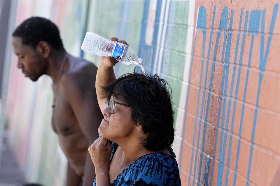 People, who are homeless, try to cool down with chilled water outside the Justa Center, a day center for homeless people 55 years and older, Friday, July 14, 2023, in downtown Phoenix. Phoenix marked the city’s 15th consecutive day of 110 degrees Fahrenheit (43.3 degrees Celsius) or higher temperatures on Friday. (AP Photo/Matt York)