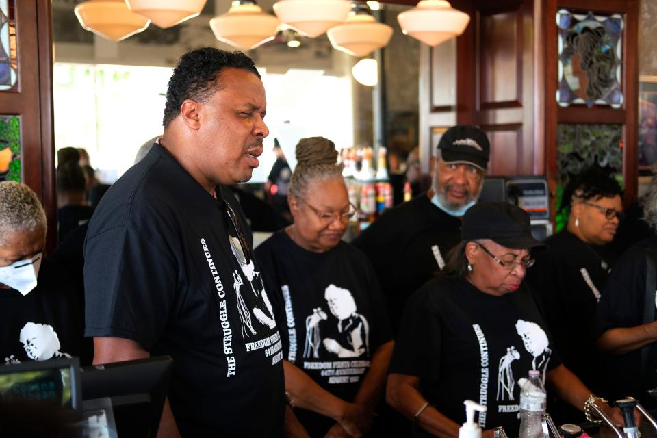 Pastor Derrick Scobey, left, closes the Clara Luper Freedom Fiesta sit-in reenactment event with a prayer. Scobey is a community organizer, activist and the pastor of Ebenezer Baptist Church.