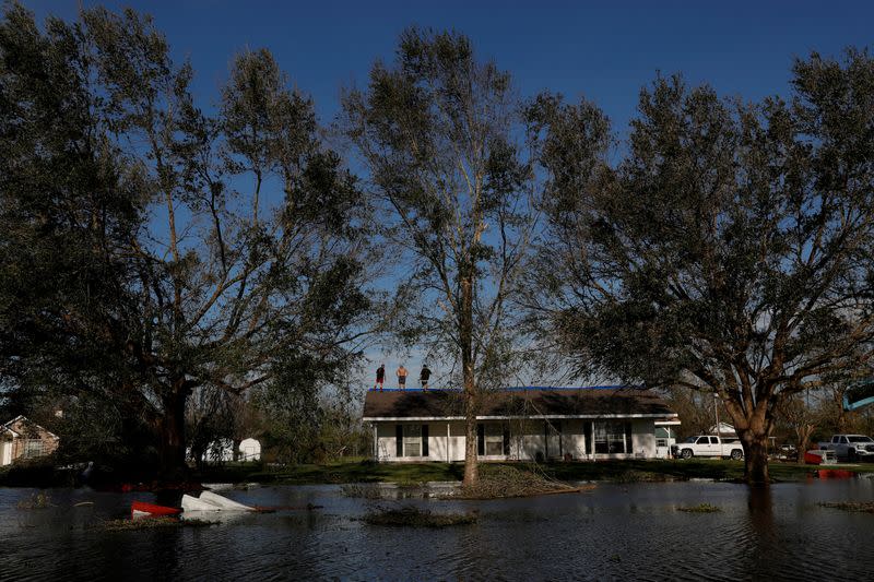 FILE PHOTO: Men stand on top of a damaged home after Hurricane Laura passed through Lake Charles, Louisiana,