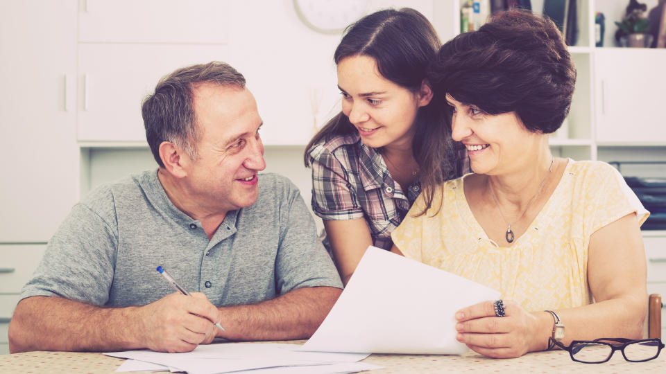 Man and woman signing documents with help of young woman indoors.