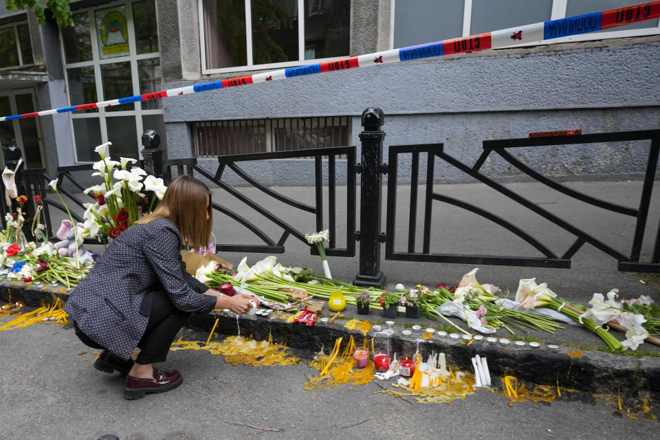 A woman lays flowers for the victims near the Vladislav Ribnikar school in Belgrade, Serbia, Thursday, May 4, 2023. A 13-year-old who opened fire Wednesday at his school in Serbia's capital. He killed multiple fellow students and a guard before calling the police and being arrested. Several children and a teacher were also hospitalized. (AP Photo/Darko Vojinovic)