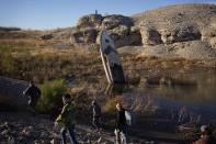 People walk by a formerly sunken boat standing upright into the air with its stern buried in the mud along the shoreline of Lake Mead at the Lake Mead National Recreation Area, Friday, Jan. 27, 2023, near Boulder City, Nev. More than 10% of the water carried by the Colorado River evaporates, leaks or spills as the 1,450-mile powerhouse river of the West flows through the region’s dams, reservoirs and open-air canals. (AP Photo/John Locher)