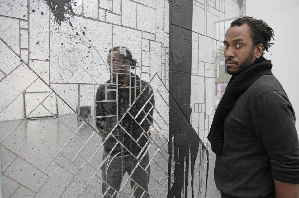 In this photo taken, Friday, April 6, 2012, artist Rashid Johnson poses with some of his work that is part of his first solo exhibition at the Museum of Contemporary Art in Chicago. In the last year, the Chicago native whose works made from everyday objects explore his own life story as well as larger issues of black identity, has garnered high-profile attention and awards from the art world. (AP Photo/M. Spencer Green)