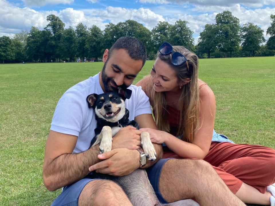 a couple takes a photo in a park with their dog