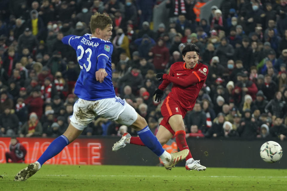 Liverpool's Takumi Minamino, right, shoots to score his sides third goal past Leicester's Jannik Vestergaard during the English League Cup quarter-final soccer match between Liverpool and Leicester City, at Anfield Stadium, in Liverpool, England, Wednesday Dec. 22, 2021. (AP Photo/Jon Super)