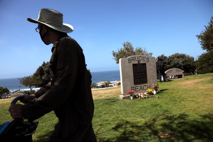 MANHATTAN BEACH, CA - APRIL 9 - - A pedestrian walks past a marker that gives the history of Bruce's Beach in Manhattan Beach on April 9, 2021. Los Angeles Supervisor Janice Hahn announced that the process of returning Bruce's Beach back to the family of Willa and Charles Bruce has begun. Sen. Steven Bradford has created SB 796 that will allow Bruce's Beach to be returned to surviving members of the Bruce family. In 1912, a young Black couple named Willa and Charles Bruce purchased beachfront property in Manhattan Beach and built a beautiful beach resort that served Black residents. It was one of the few beaches where Black residents could go because so many other local beaches did not permit Black beachgoers. The Bruce's and their customers were harassed and threatened by white neighbors including the KKK. Eventually, the Manhattan Beach City Council moved to seize the property using eminent domain, purportedly to create a park. The Council took the property in 1929 and it remained empty for many years. The property the Bruce's once owned was years later transferred to the State and in 1995 transferred to Los Angeles County. It is now the site of the Los Angeles County Lifeguard Training Headquarters. APRIL 09: Manhattan Beach Friday, April 9, 2021 Manhattan Beach, CA. (Genaro Molina / Los Angeles Times)