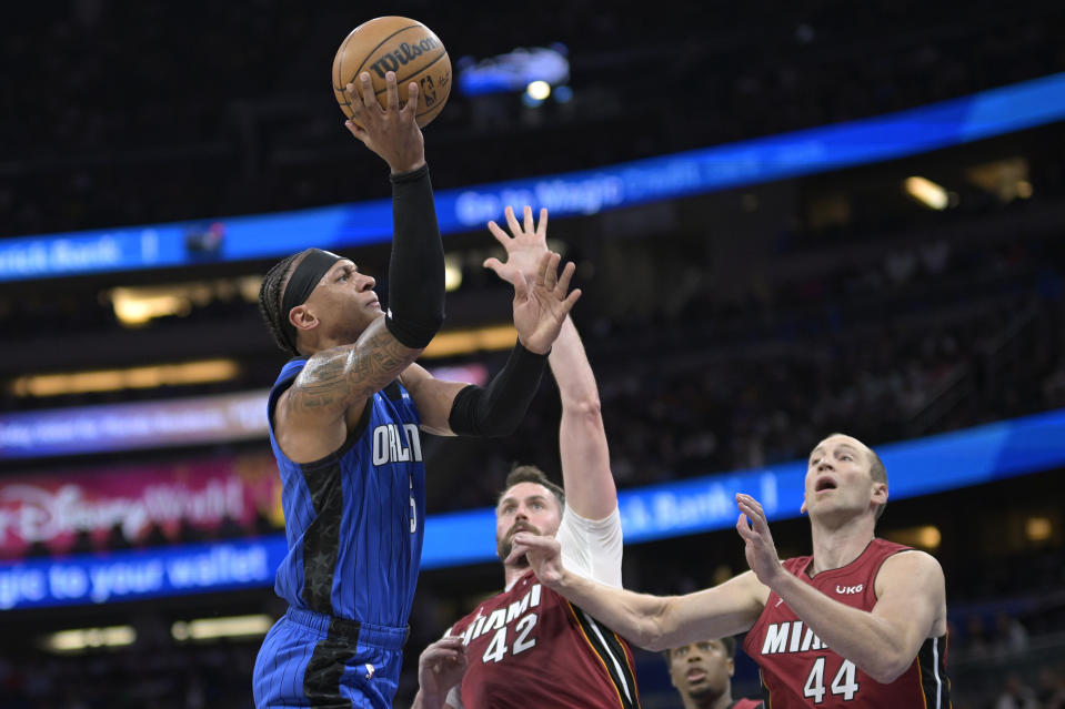 Orlando Magic forward Paolo Banchero, left, goes up to shoot in front of Miami Heat forward Kevin Love (42) and center Cody Zeller (44) during the first half of an NBA basketball game, Saturday, March 11, 2023, in Orlando, Fla. (AP Photo/Phelan M. Ebenhack)