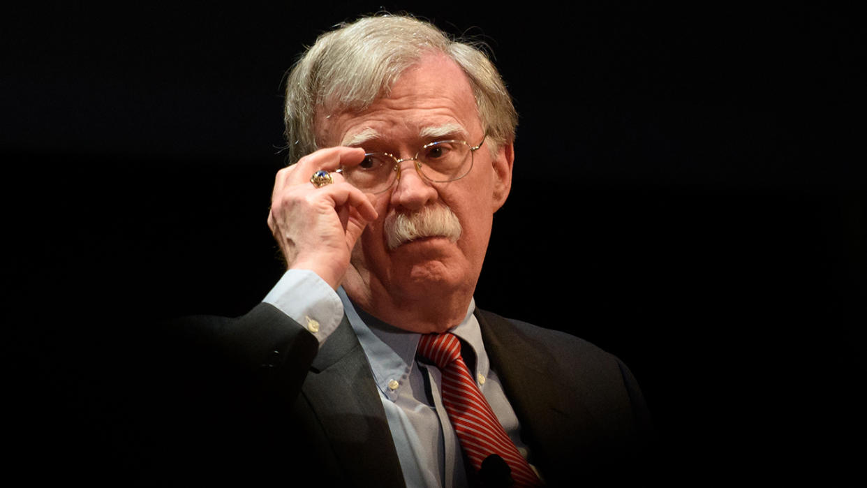 John Bolton adjusts his eyeglasses.