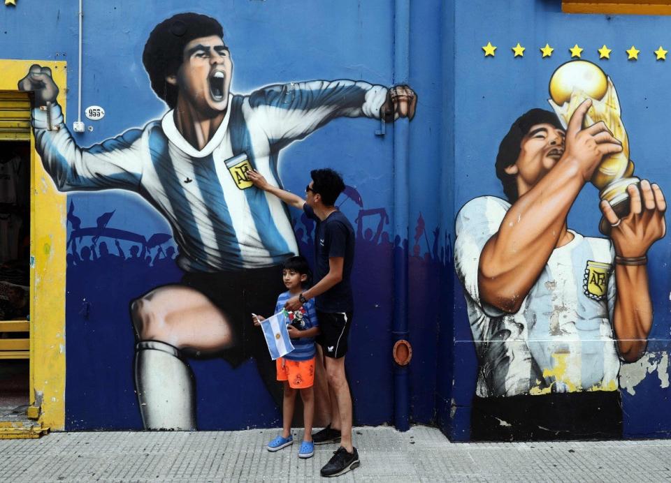 A man and his child pay tribute next to a mural depicting MaradonaAFP via Getty Images