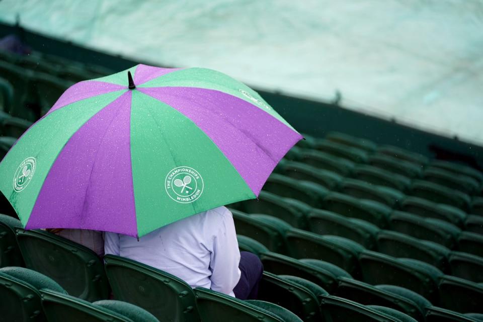 Spectators shelter from the rain on day one of Wimbledon (Zac Goodwin/PA) (PA Wire)