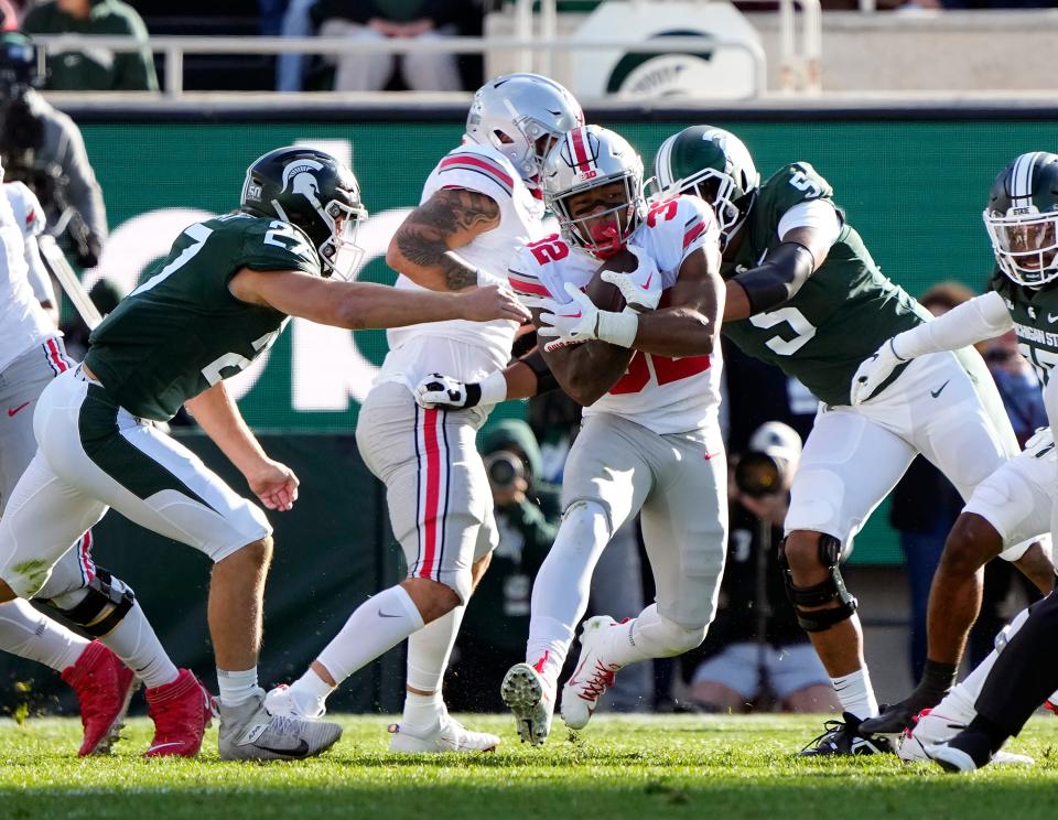 Oct 8, 2022; East Lansing, Michigan, USA; Ohio State Buckeyes running back TreVeyon Henderson (32) carries the ball past Michigan State Spartans linebacker Cal Haladay (27) in the second quarter of the NCAA Division I football game between the Ohio State Buckeyes and Michigan State Spartans at Spartan Stadium. 