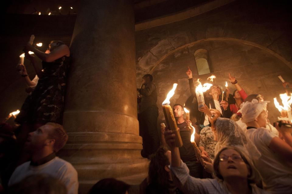 Christian pilgrims hold candles at the church of the Holy Sepulcher, traditionally believed to be the burial site of Jesus Christ, during the ceremony of the Holy Fire in Jerusalem's Old City, Saturday, April 19, 2014. The "holy fire" was passed among worshippers outside the Church and then taken to the Church of the Nativity in the West Bank town of Bethlehem, where tradition holds Jesus was born, and from there to other Christian communities in Israel and the West Bank. (AP Photo/Dan Balilty)