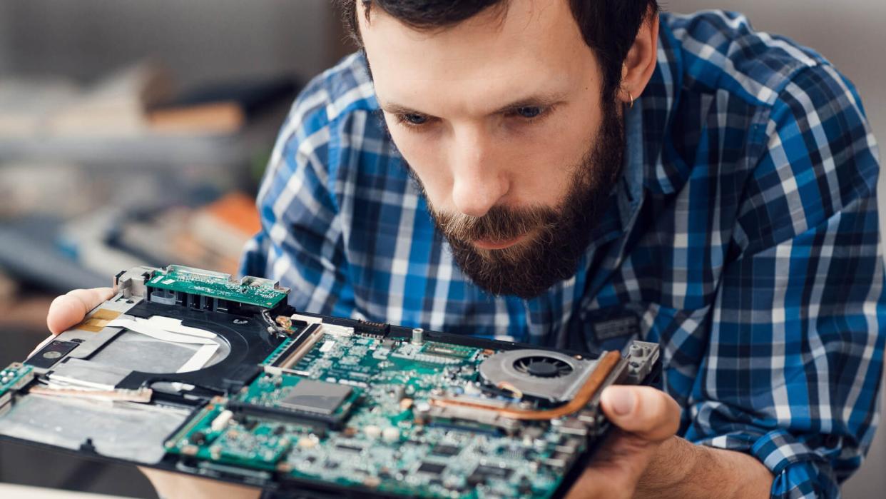 Engineer studying computer motherboard, close-up.