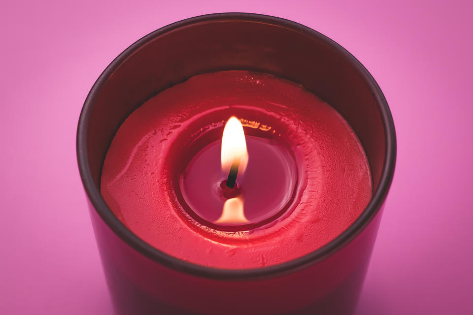 Candle flame close-up. Aromatherapy concept. Romantic atmosphere. Burning red candle on a pink background