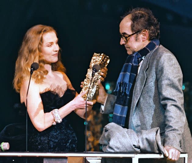 Isabelle Huppert presents a César Award to Godard in 1987. (Photo: MICHEL GANGNE via Getty Images)