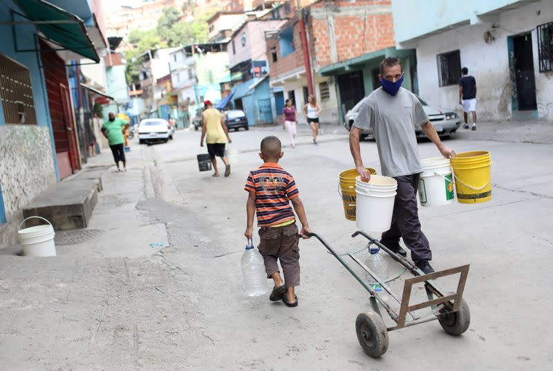FILE PHOTO: People walk with plastic containers near an unknown water source in the low-income neighbourhood of Petare amid the coronavirus disease (COVID-19) outbreak in Caracas