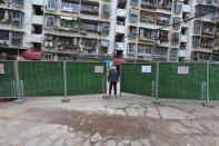 FILE PHOTO: Man wearing a face mask keeps watch at an entrance to a residential community that has been fenced in with temporary barriers, in Yichang city of Hubei