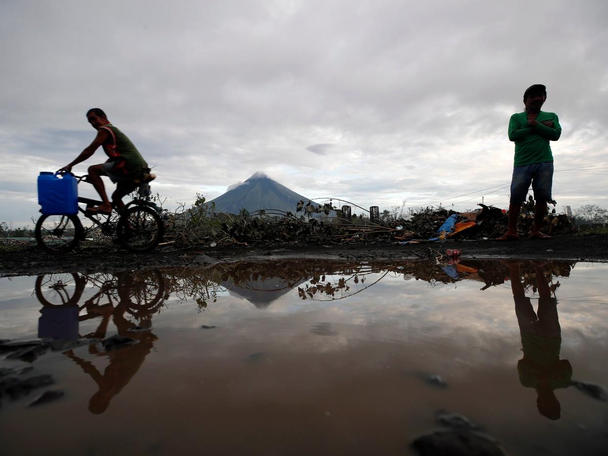 Villagers wade on flood water brought by a lahar flow due to typhoon Goni at the foot of Mayon volcano in The Philippines (EPA)