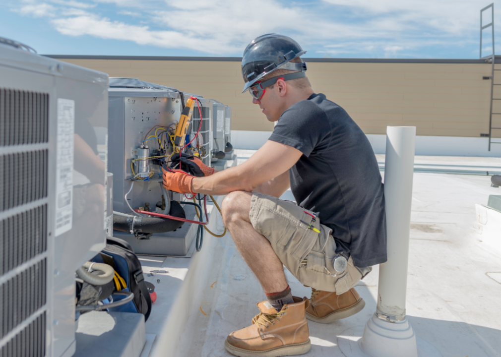 HVAC tech checking on condensing unit on roof