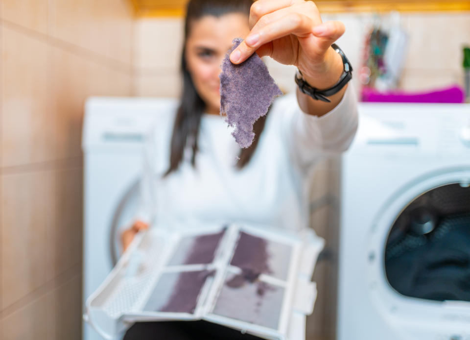 Young woman is removing lint from fluff dust filter of the tumble dryer. Dust and dirt trapped by the clothes dryer filter. Laundry processes