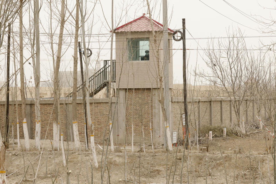 A security person watches from a guard tower around a detention facility in Yarkent County in northwestern China's Xinjiang Uyghur Autonomous Region on March 21, 2021. Four years after Beijing's brutal crackdown on largely Muslim minorities native to Xinjiang, Chinese authorities are dialing back the region's high-tech police state and stepping up tourism. But even as a sense of normality returns, fear remains, hidden but pervasive. (AP Photo/Ng Han Guan)