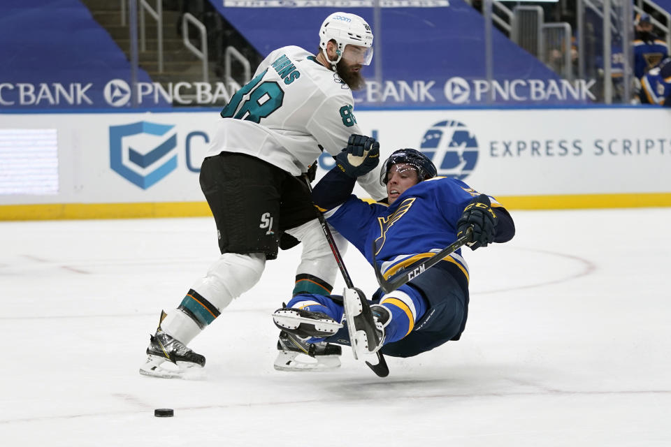 St. Louis Blues' David Perron, right, slips as San Jose Sharks' Brent Burns defends during overtime of an NHL hockey game Wednesday, Jan. 20, 2021, in St. Louis. (AP Photo/Jeff Roberson)