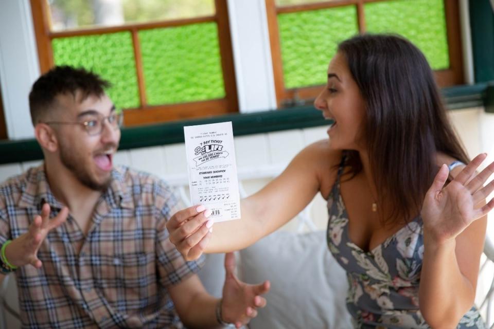 Couple holds up winning lottery ticket on the couch