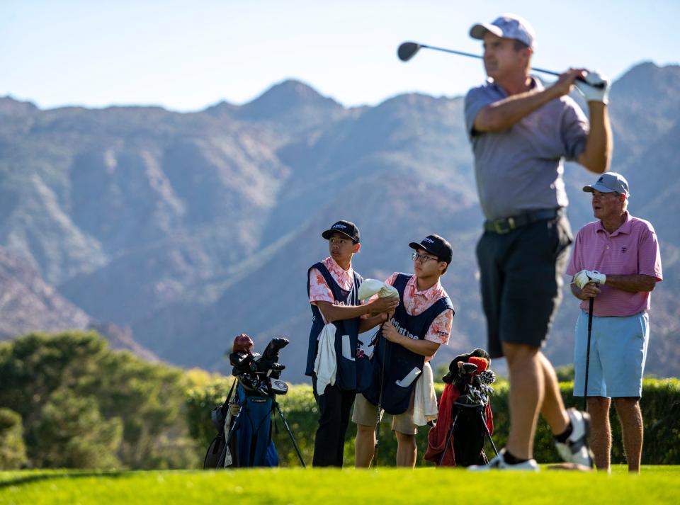 First Tee caddies Brighton Cariaga (left) and Alex Yang watch a golfer in their group tee off to start their round at Ironwood Country Club in Palm Desert, Calif., Saturday, Nov. 18, 2023.