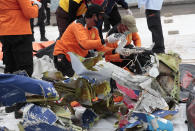 Workers sort parts of aircraft and debris retrieved from from the Java Sea where a Sriwijaya Air jet crashed on Saturday, to be arranged and examined by investigators at Tanjung Priok Port in Jakarta, Indonesia, Thursday, Jan. 14, 2021. An aerial search for victims and wreckage of a crashed Indonesian plane expanded Thursday as divers continued combing the debris-littered seabed looking for the cockpit voice recorder from the lost Sriwijaya Air jet. (AP Photo/Dita Alangkara)