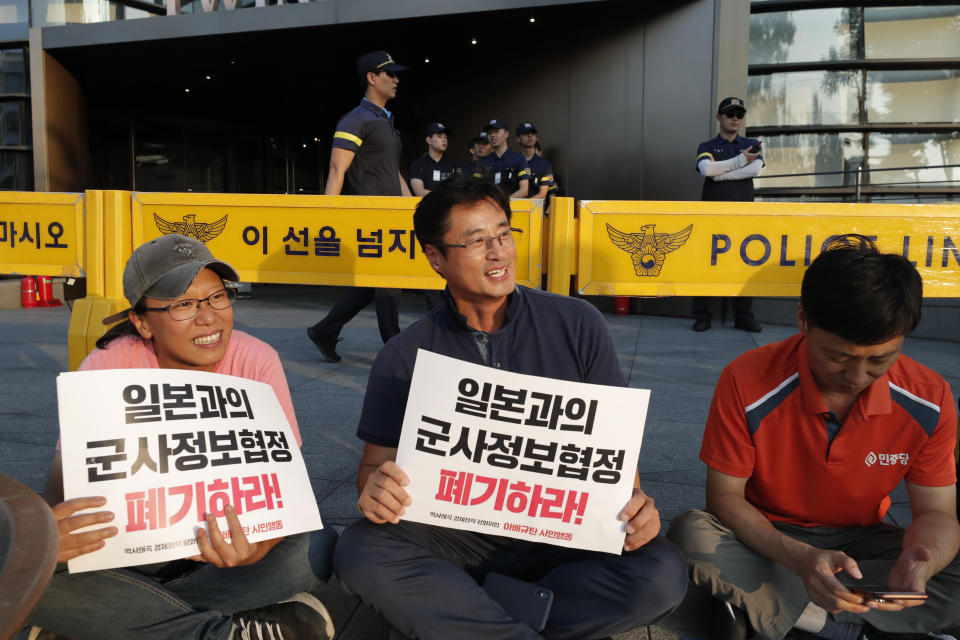 South Korean protesters react after they listen the news reporting about the General Security of Military Information Agreement, or GSOMIA, in front of Japanese embassy in Seoul, South Korea, Thursday, Aug. 22, 2019. South Korea says it is canceling an intelligence-sharing pact with Japan amid a bitter trade dispute with its Asian neighbor. The letters read "Abolish the General Security of Military Information Agreement, or GSOMIA." (AP Photo/Lee Jin-man)