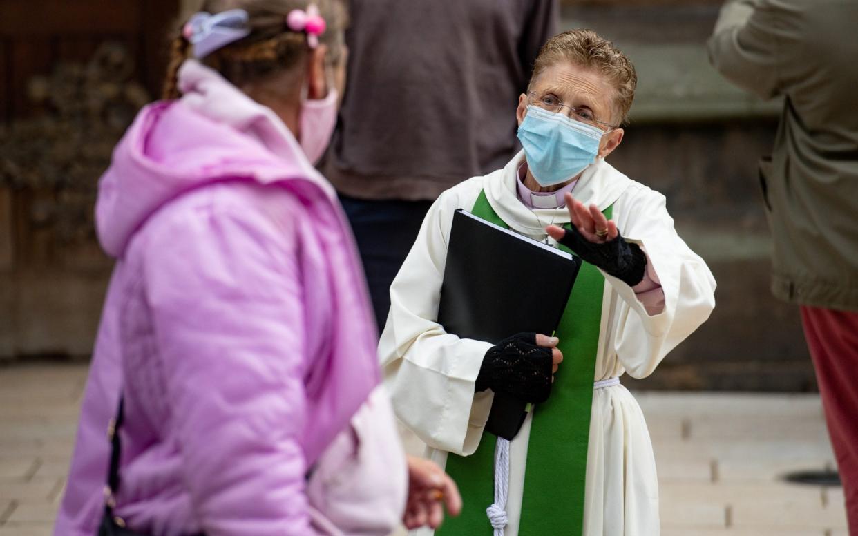 A priest wearing PPE speaks to a member of the St Martin congregation in Birmingham city centre  - PA