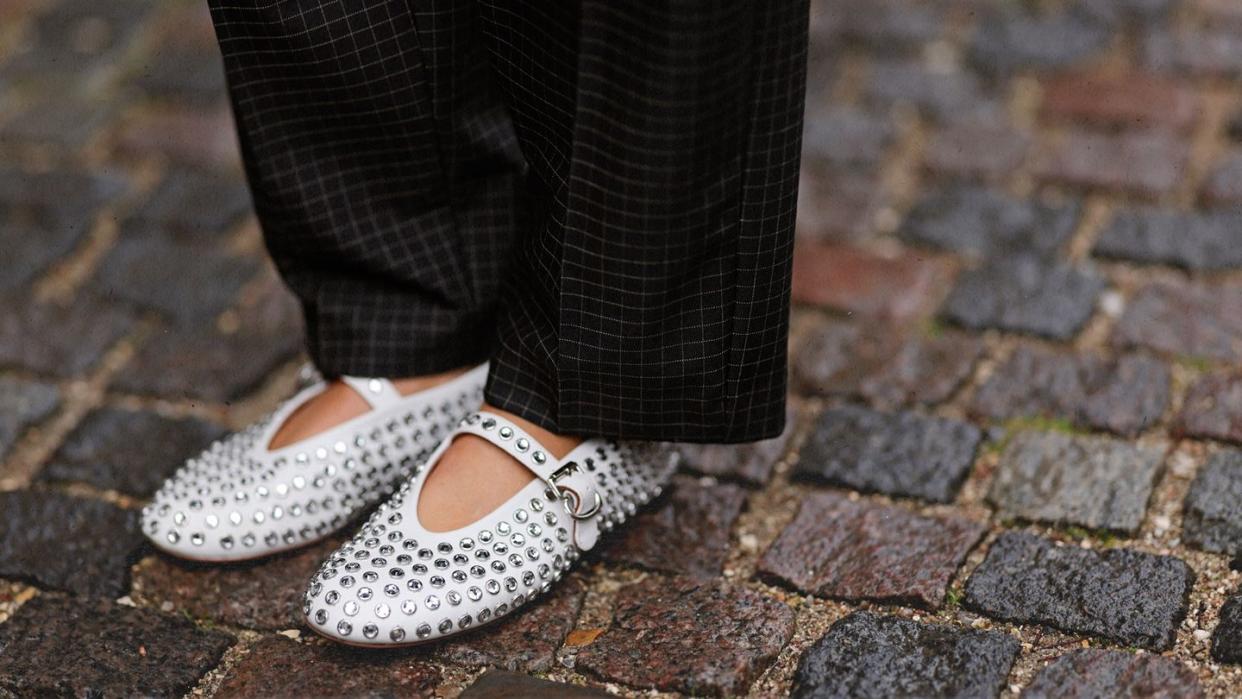 a person's feet in white shoes on a brick surface