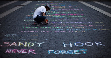 FILE PHOTO: Street artist Mark Panzarino, 41, prepares a memorial as he writes the names of the Sandy Hook Elementary School victims during the six-month anniversary of the massacre, at Union Square in New York, June 14, 2013. REUTERS/Eduardo Munoz/File Photo