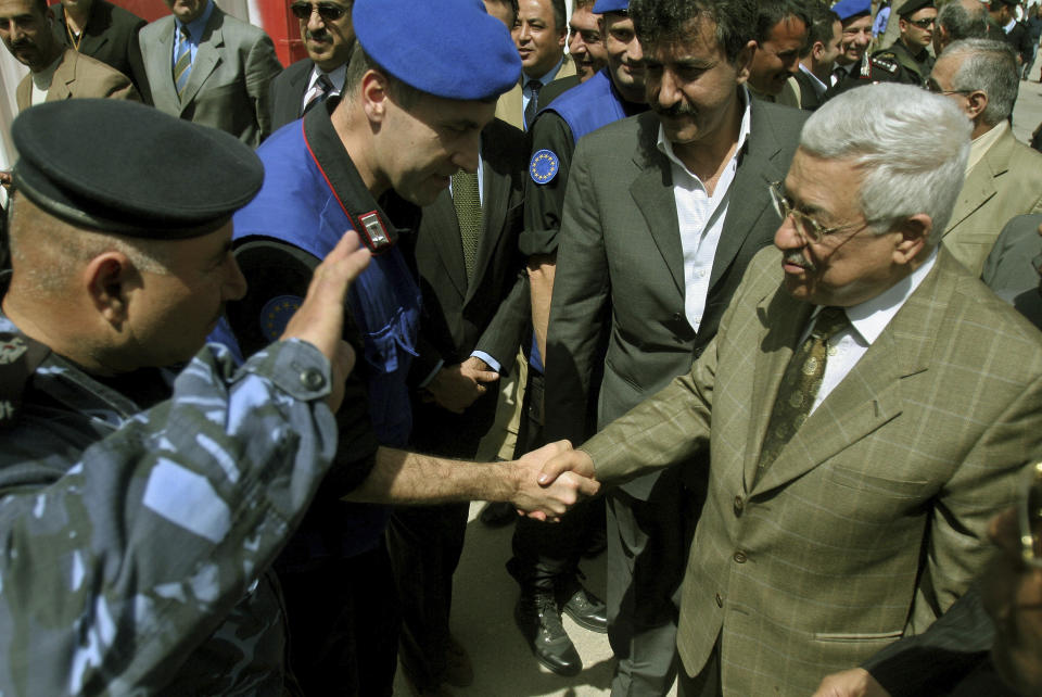 FILE - Palestinian leader Mahmoud Abbas, also known as Abu Mazen, right, shakes hands with a member of European Union's border monitoring mission during his visit to the Rafah crossing border between Gaza Strip and Egypt, Sunday, March 19, 2006. The European Union withdrew the monitoring mission formed to promote a two-state solution between Israel and the Palestinians from Gaza after the Hamas militant group seized power in 2007. But 16 years later, the mission continues to maintain offices in Israel in hopes of one day returning. Critics say the ongoing Western commitment to the two-state solution fails to recognize the changing circumstances in the region and maintains a costly-status quo. (AP Photo/Khalil Hamra, Pool, File )