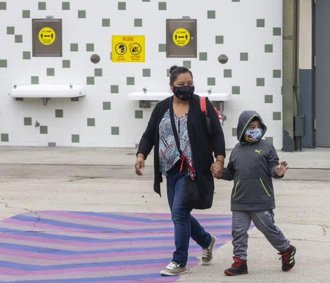 Los Angeles, CA - July 26: First grade student Daniel Cano, 5, and his mom, Sonia Cano, walk past COVID-19 safety precaution/ social distancing and hand washing signs at the drinking fountain at a L.A. Unified "meet and greet" with its medical advisors as they answer questions and present the safety preparations at Euclid Avenue Elementary School Monday, July 26, 2021 in Los Angeles, CA. Parents have until Friday to choose whether to return their children to in-person classes or remain online in the fall. The first day of school is in mid-August. (Allen J. Schaben / Los Angeles Times)